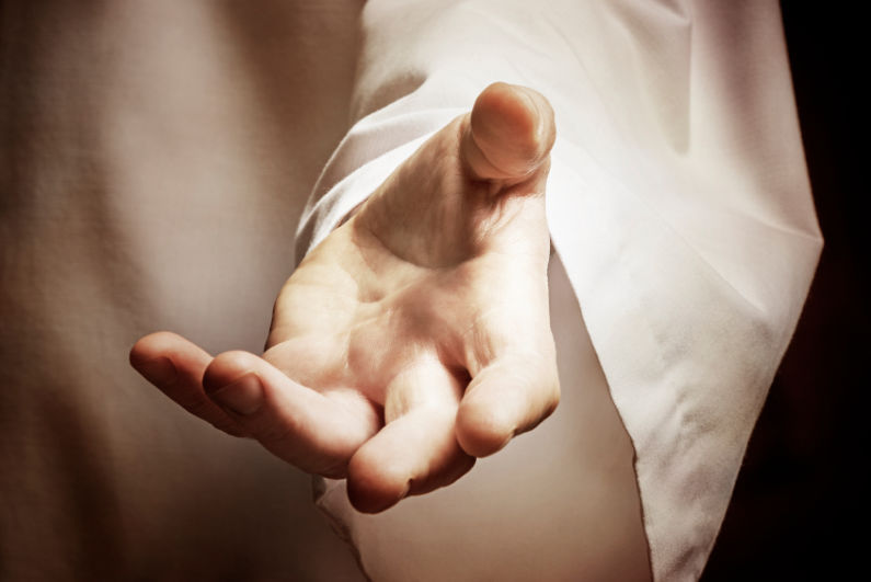 A close-up shot of a person's outstretched hand, palm up and open in a gesture of offering, welcoming, or help, wearing a flowing white robe.