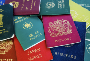 A high-angle, close-up shot of several international passports from different countries, including India, Japan, the Republic of Korea, and the United Kingdom, scattered in a colorful pile.
